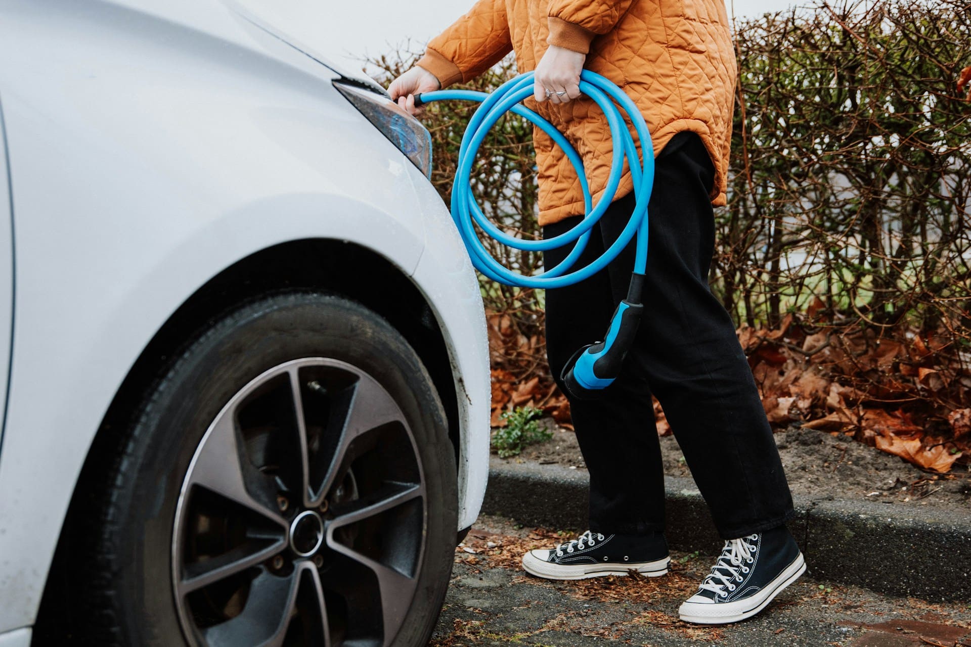 Une personne déroule le câble de recharge électrique bleu de sa voiturele