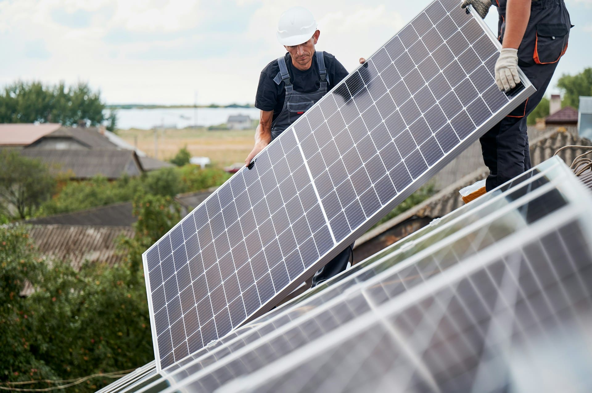Deux installaterus de panneaux solaires transportent un panneau