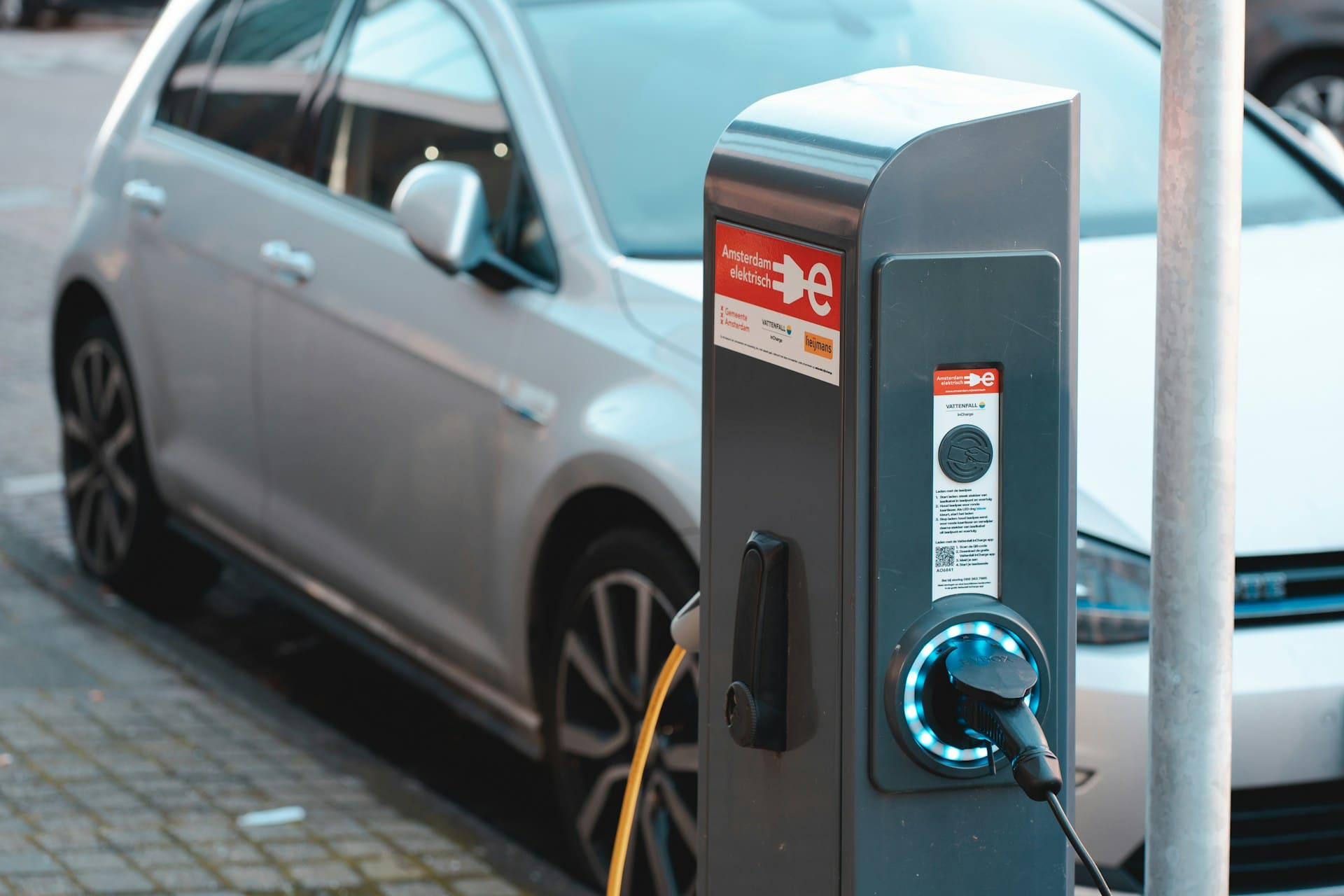 Une voiture blanche se fait recharger par une borne de recharge