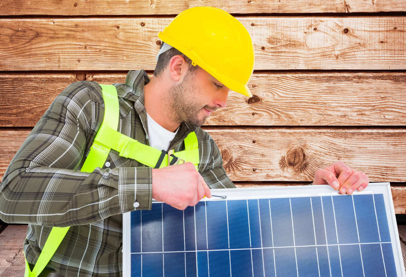 personne portant un casque jaune tient un panneau solaire