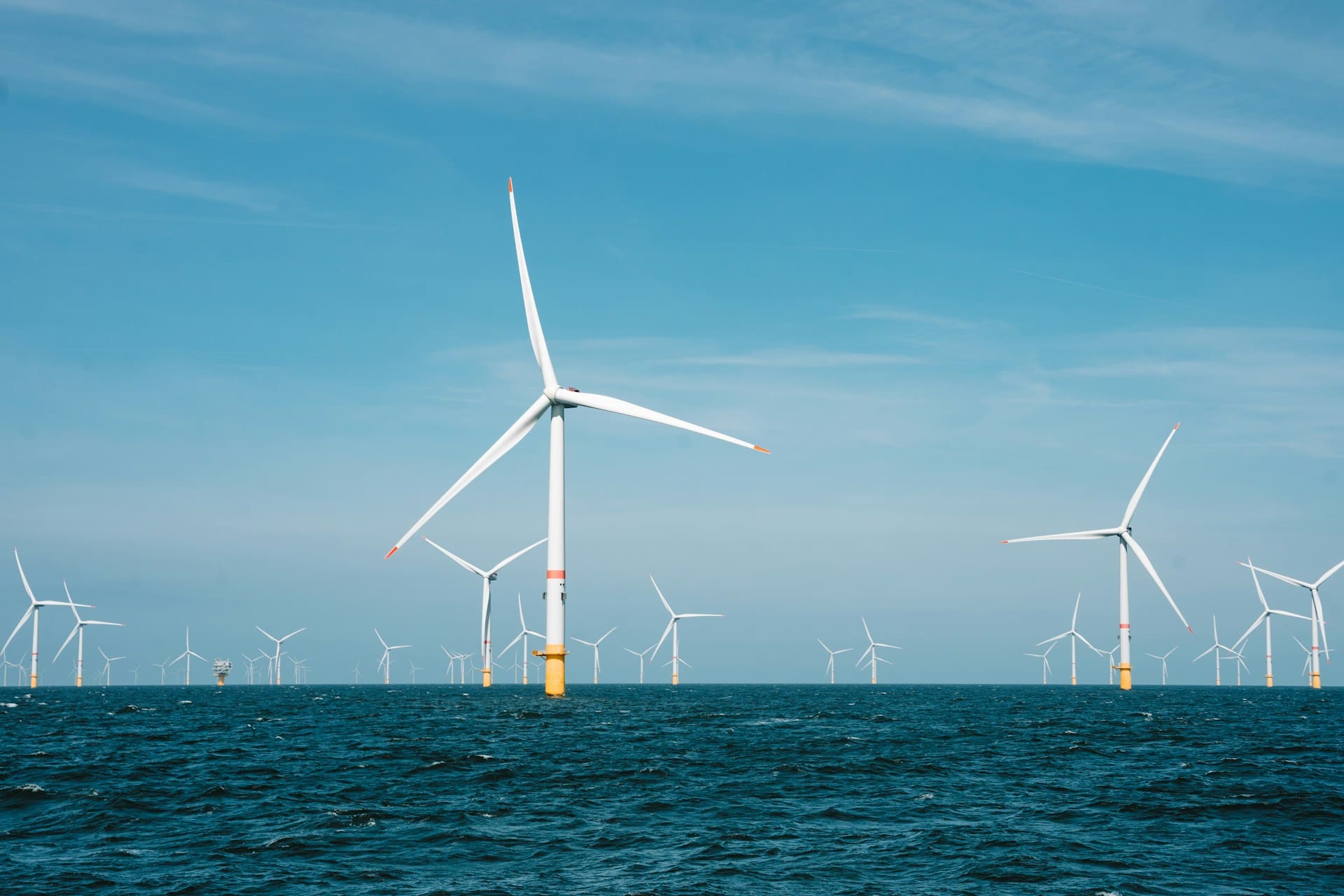 Une dizaine d'éolienne en mer sous un ciel bleu