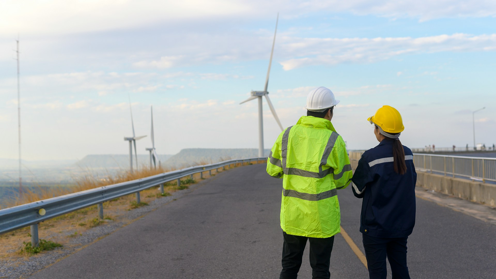 Deux installateurs font face à un champ d'éolienne