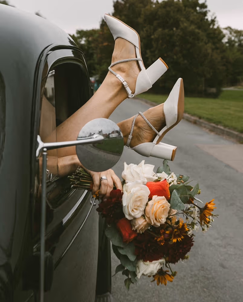 Wedding shoes and flowers coming out of a car window