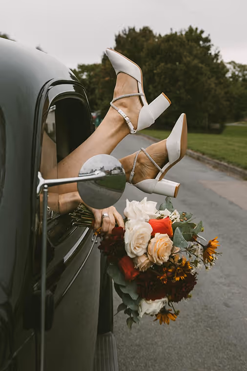 Wedding shoes and flowers coming out of a car window