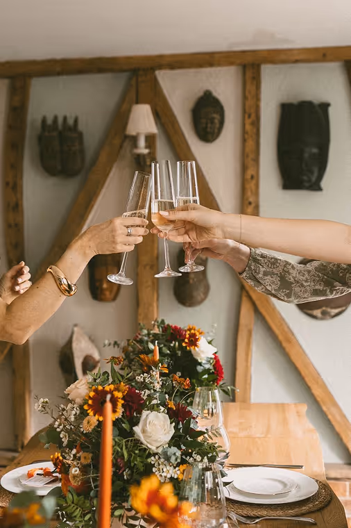 Three glasses being clinked together above event flowers