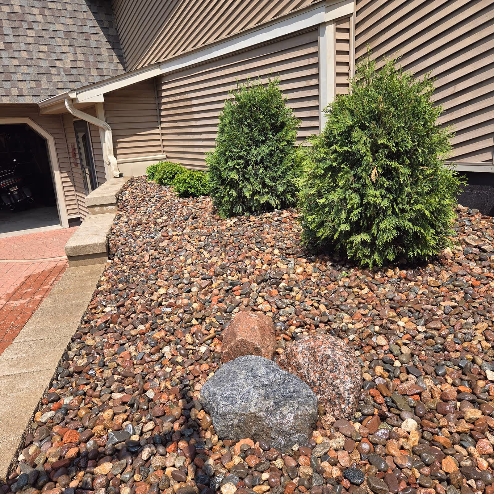 Decorative stone and mulch bed around foundation plantings in Waukesha County