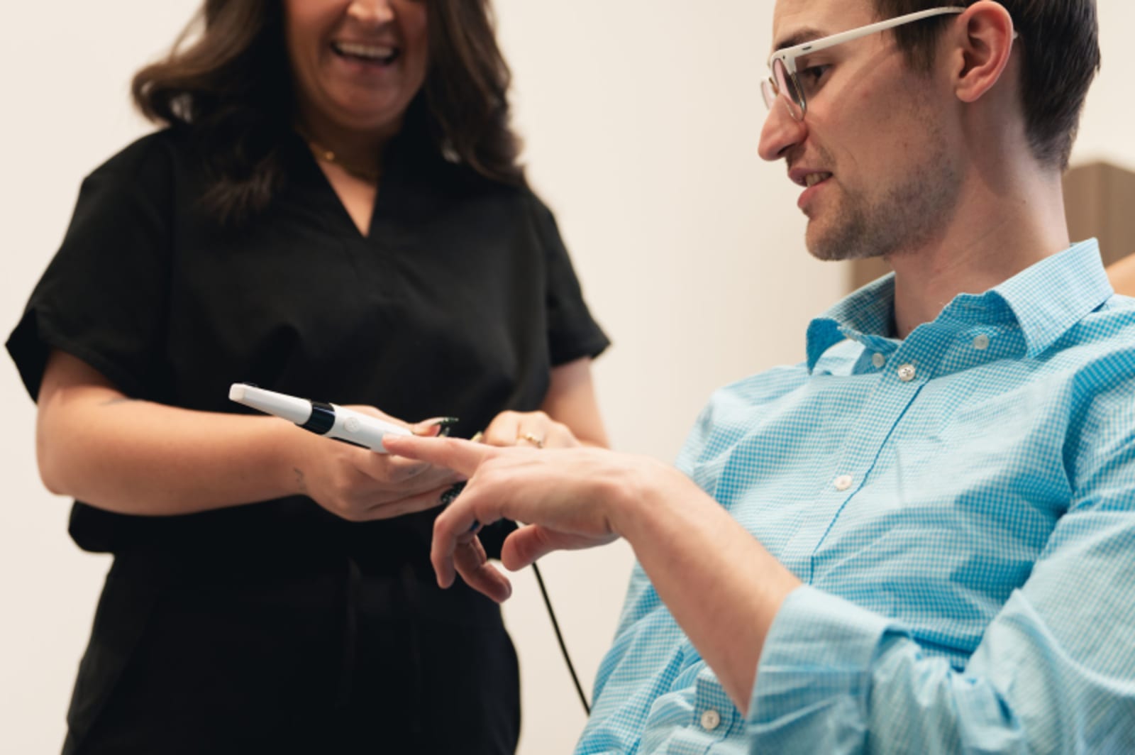 Female team member in scrubs presenting smile consultation device to patient