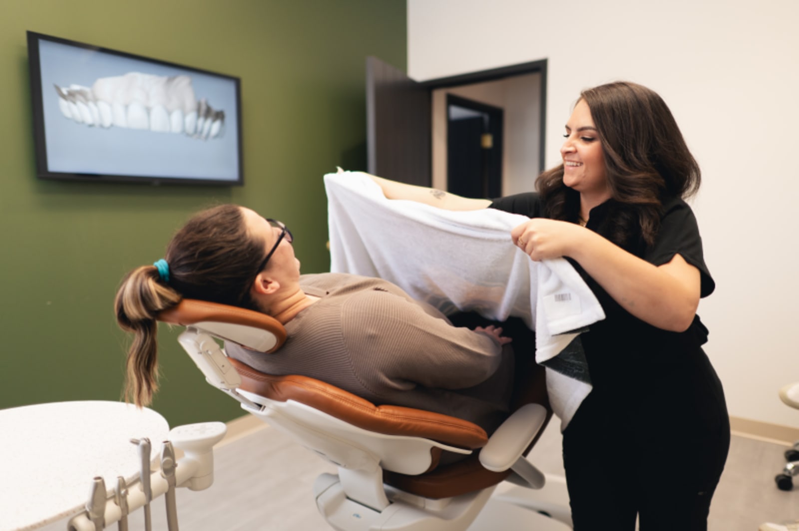 Dentist guiding patient through treatment positioning and preparation in dental chair