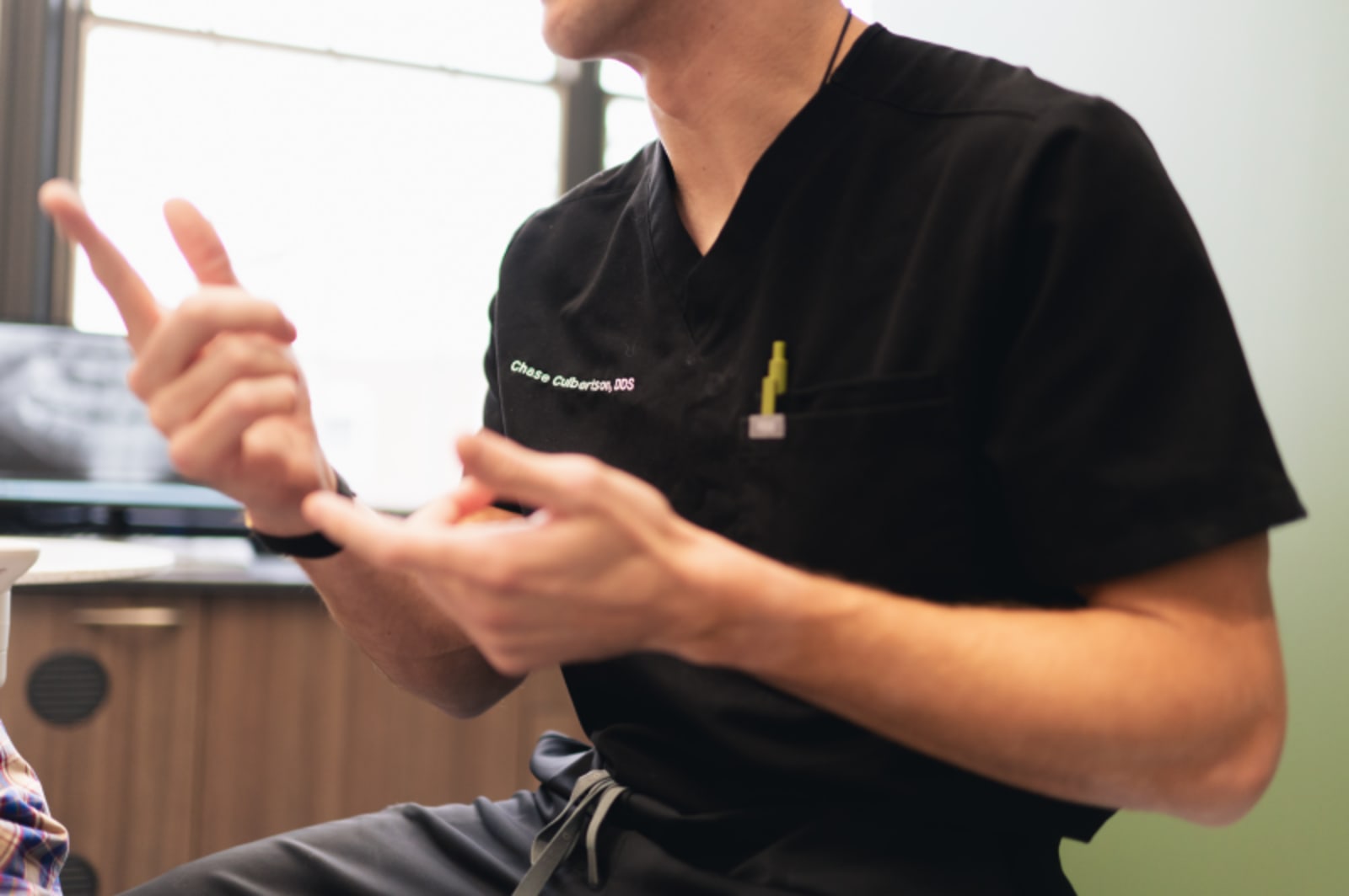 Dentist explaining procedure steps to patient in black scrubs during consultation
