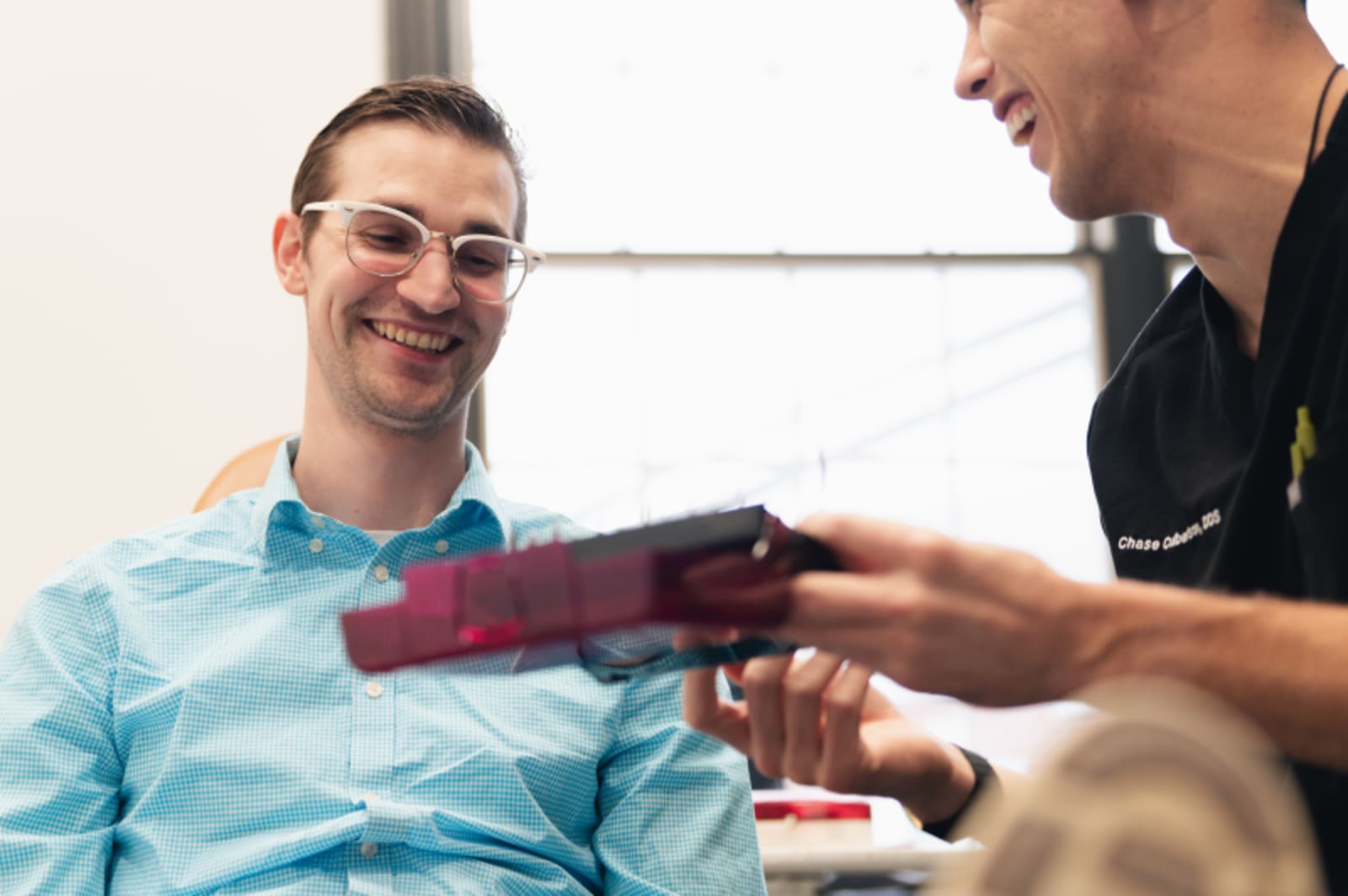 Dentist showing intraoral scanner or treatment tool to patient during consultation