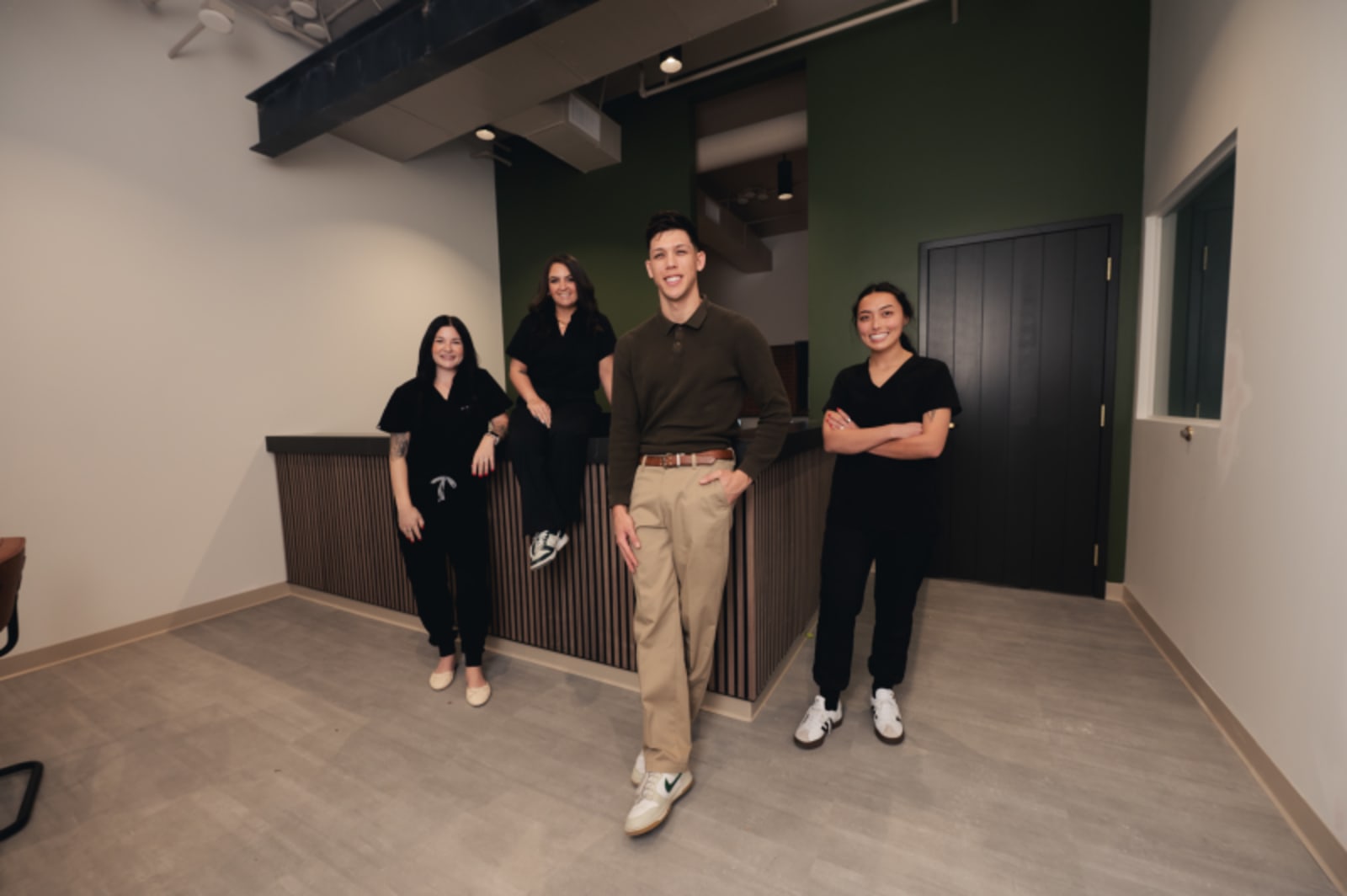 Dental team of three professionals standing together in modern clinical space