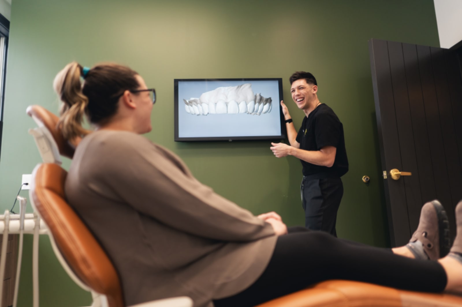 Dentist in clinical setting examining patient in dental chair with treatment in progress