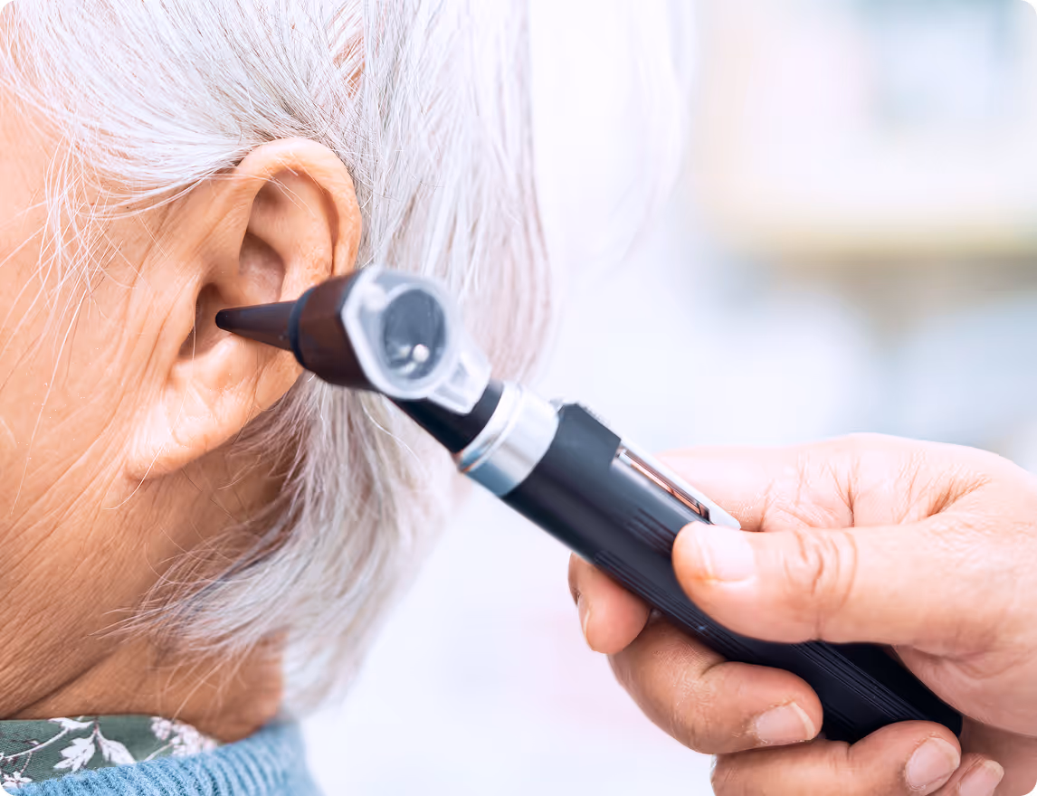Medical professional using otoscope to examine senior patient's ear