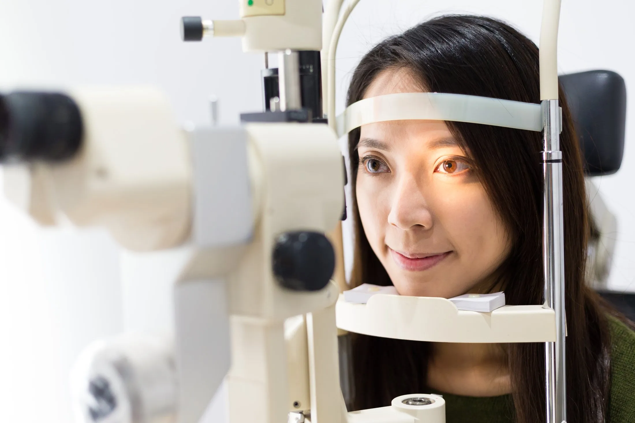 Woman undergoing eye exam with optical equipment in healthcare setting