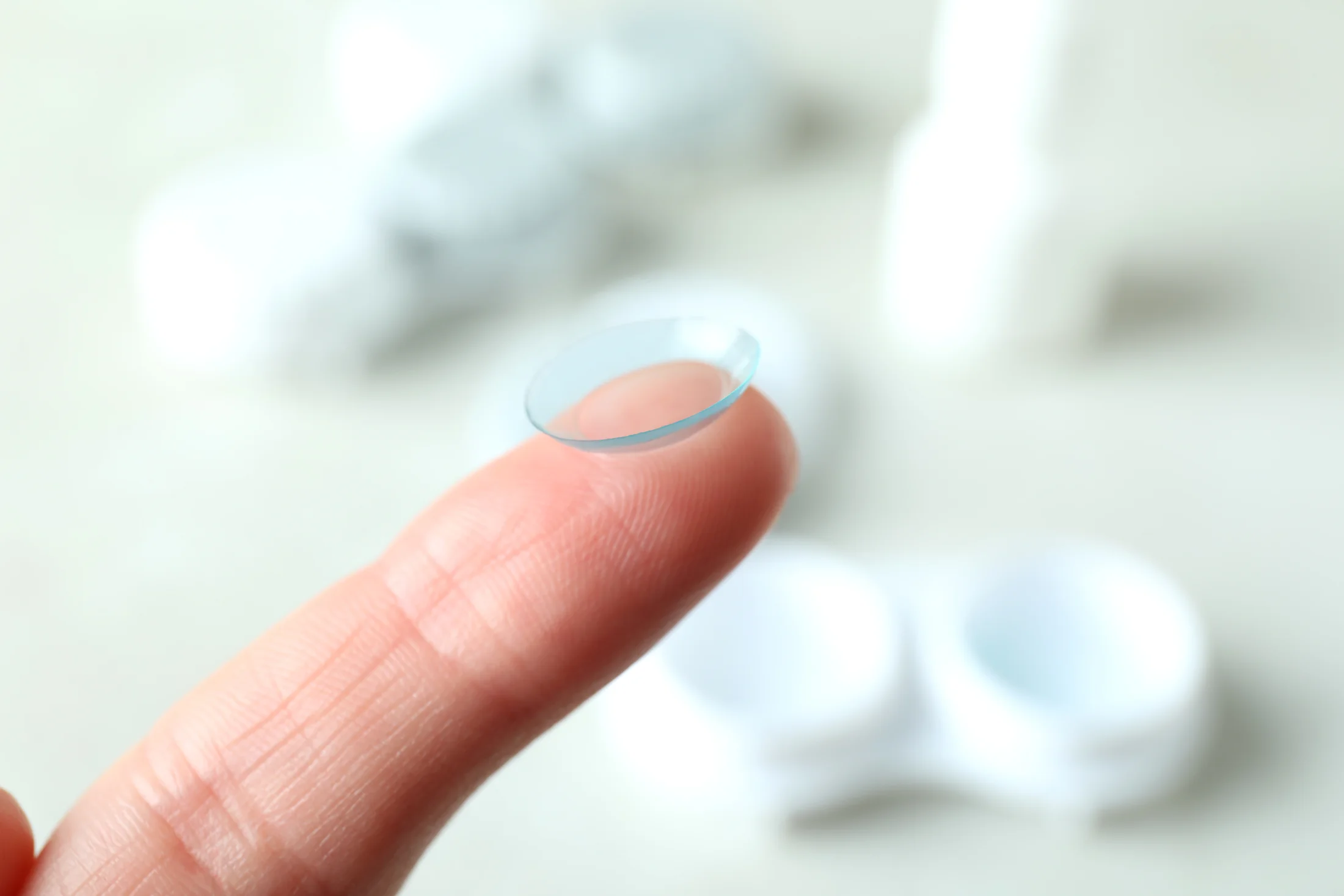 Thin, transparent contact lens balanced delicately on fingertip