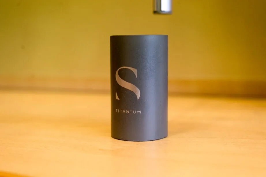 Gray cylindrical Titanium product container with large S logo