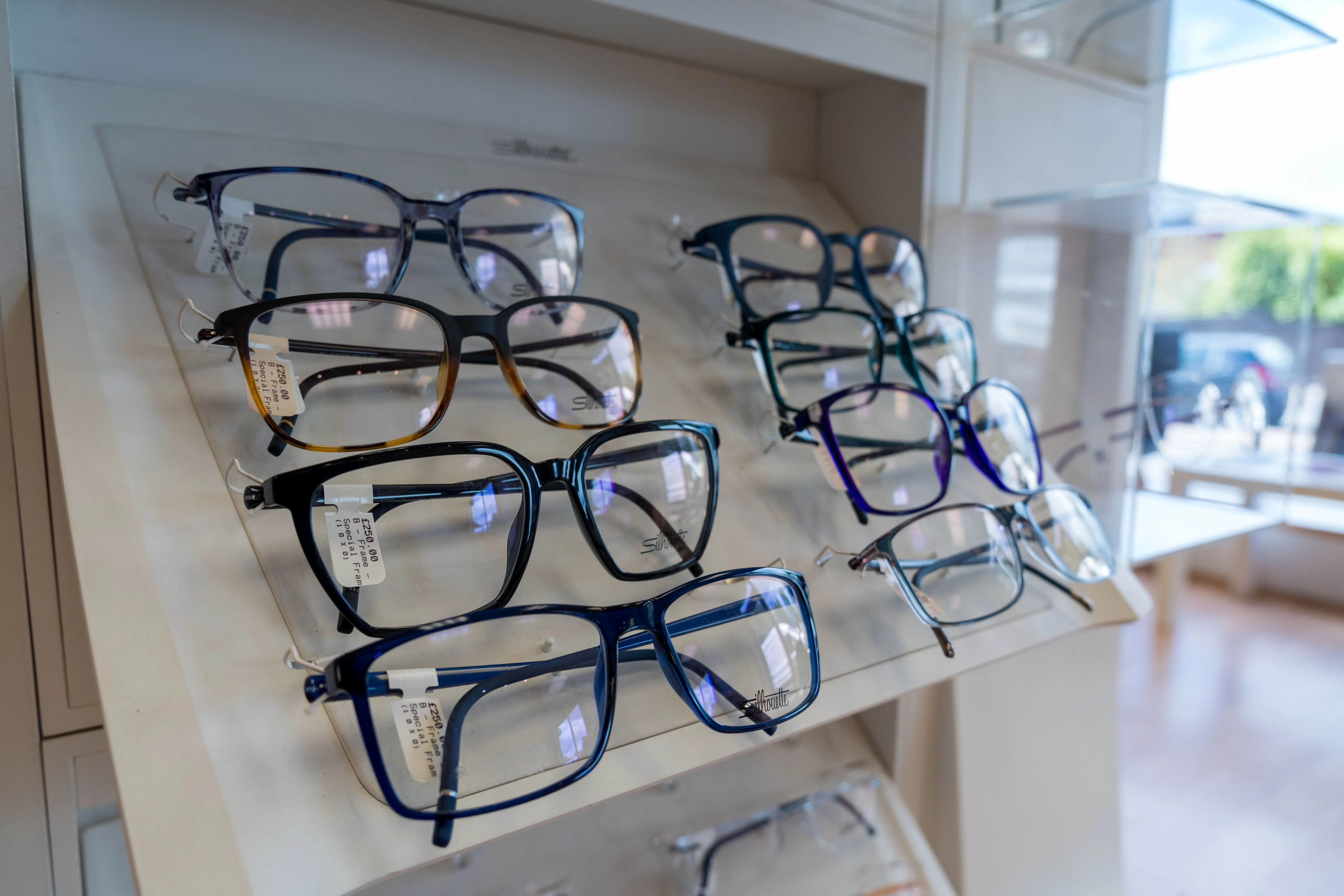 Multiple pairs of eyeglasses displayed on shelves in an optical store