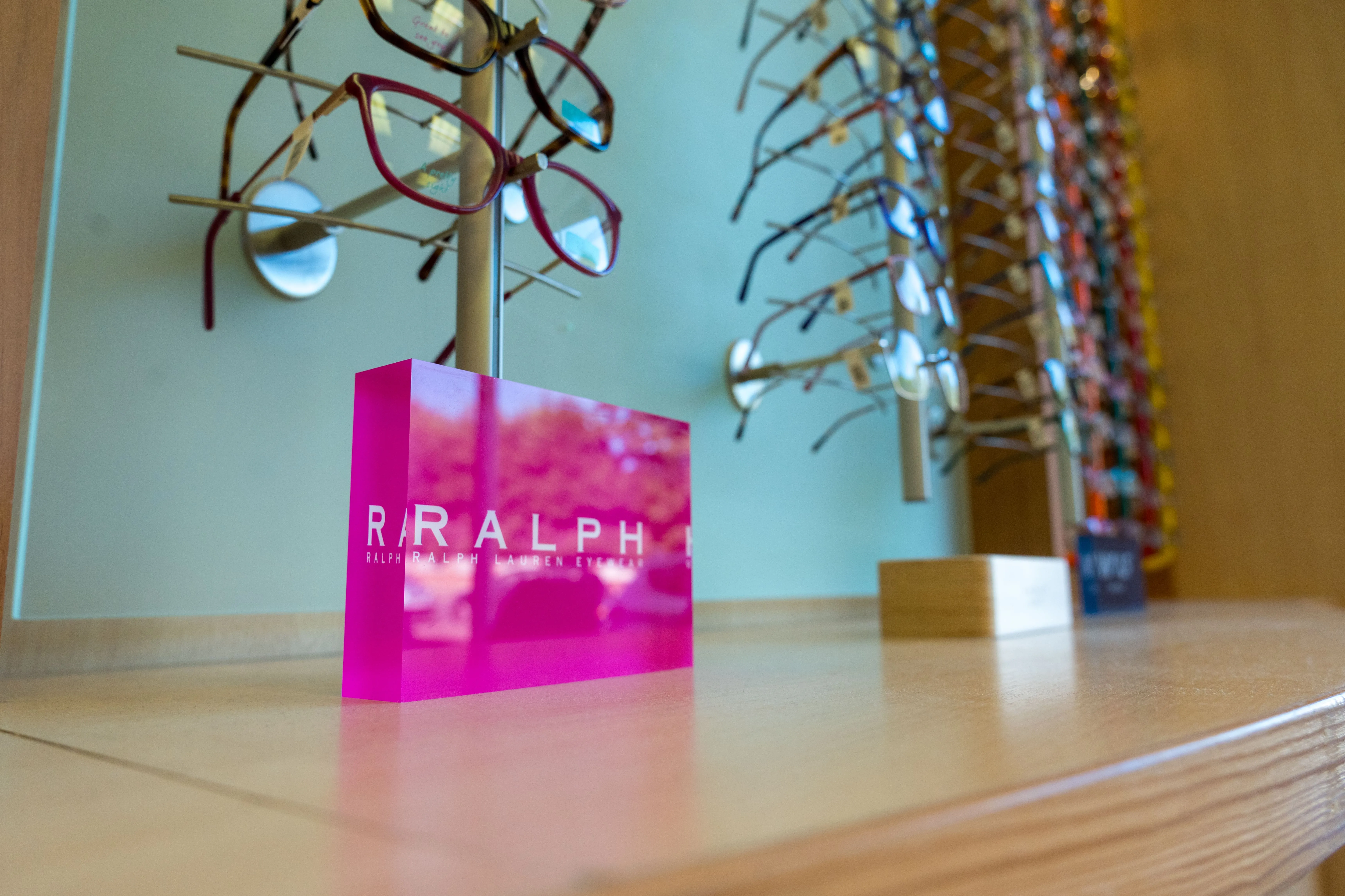 Bright pink Ralph Lauren sign with eyeglasses display in background