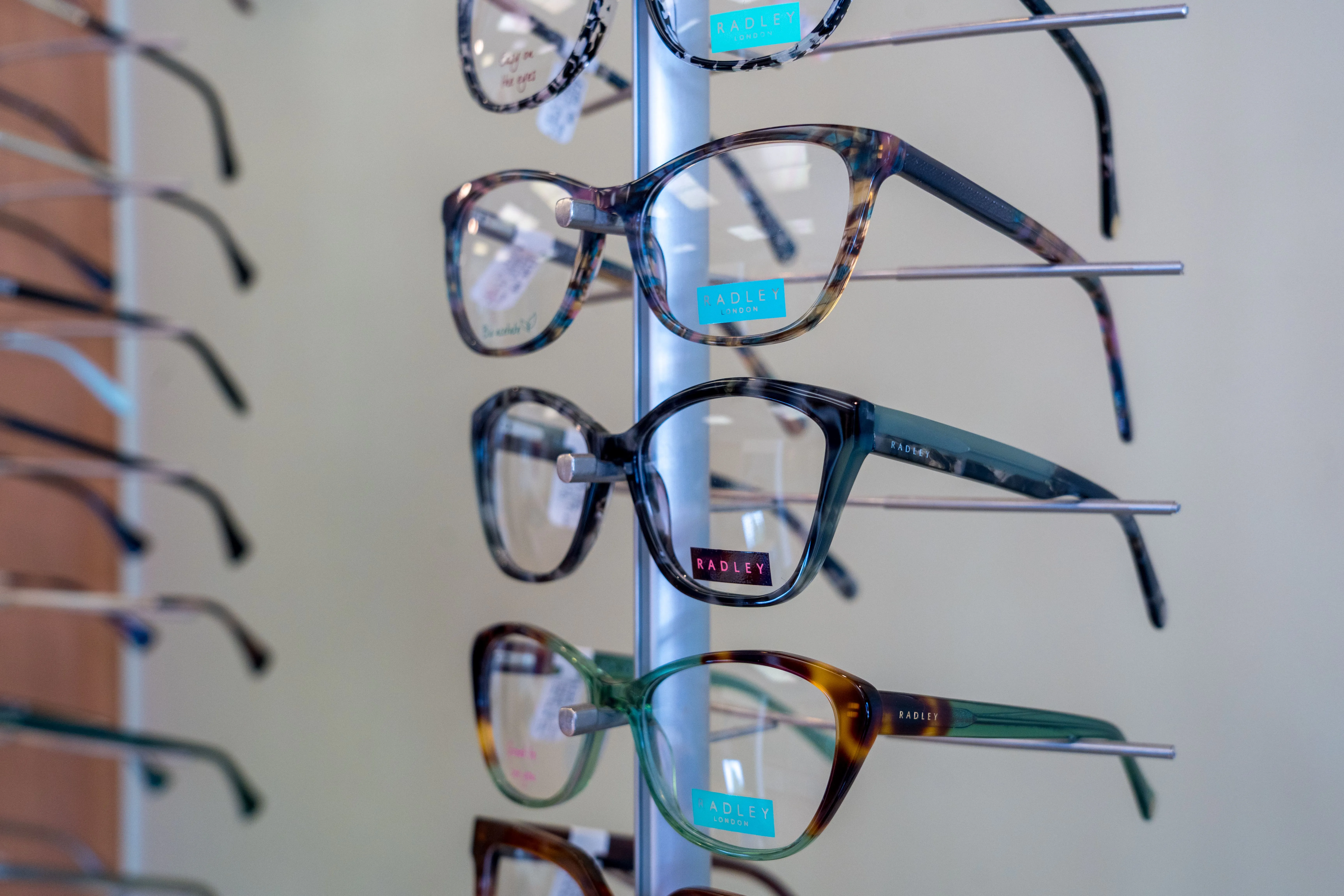 Radley eyeglasses display with multiple colorful frames on a vertical stand