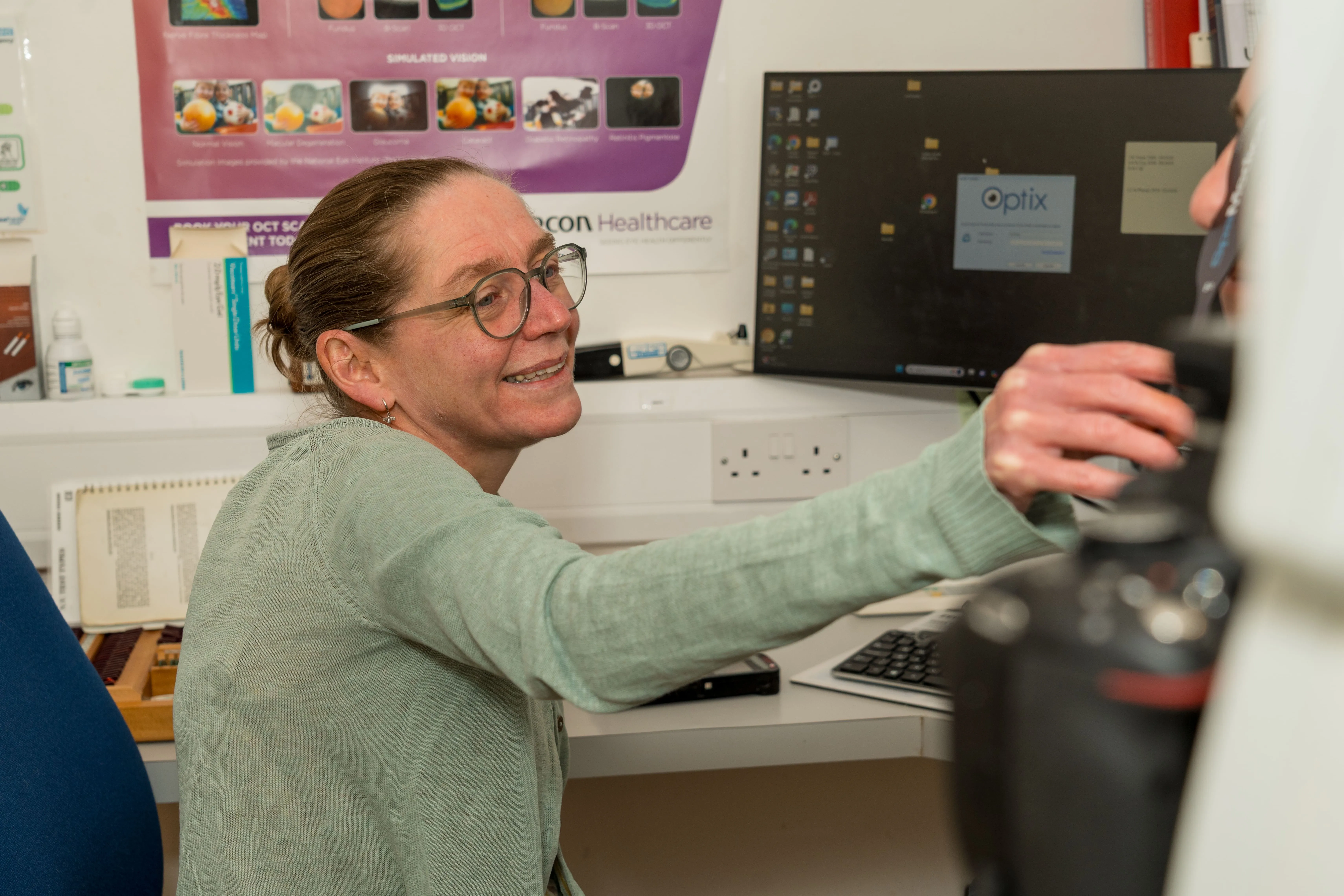 Smiling healthcare worker using computer in medical office with Optix software