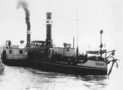 Black and white photo of a steamship with a smokestack emitting smoke on water.