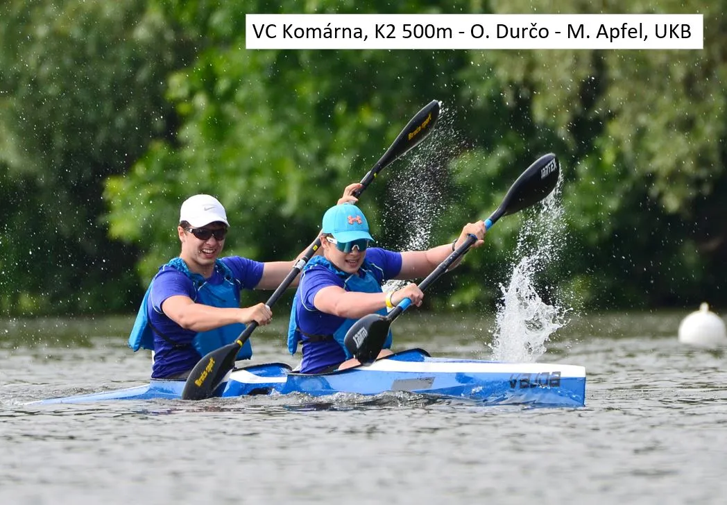 Two athletes paddling a blue kayak in a 500m K2 race, splashing water during vigorous rowing.