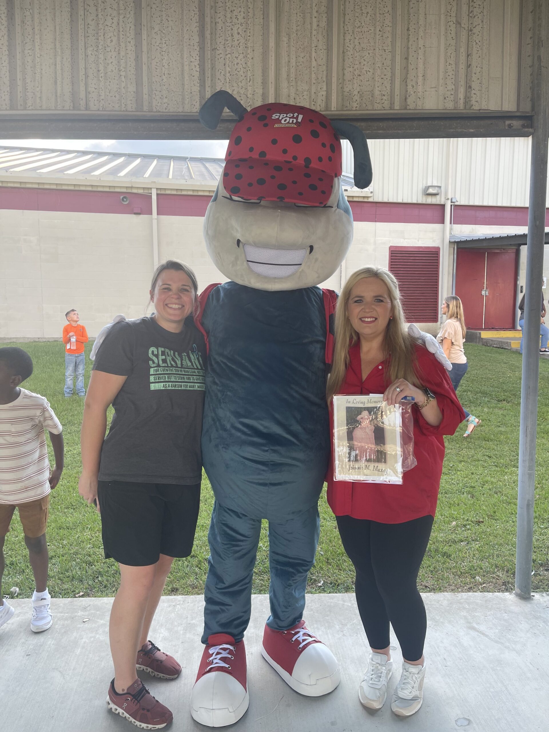 Two women pose with ladybug mascot.