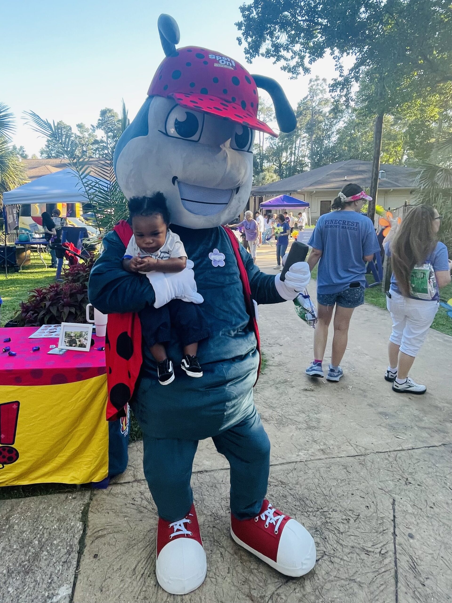 Mascot holding a small child outdoors.