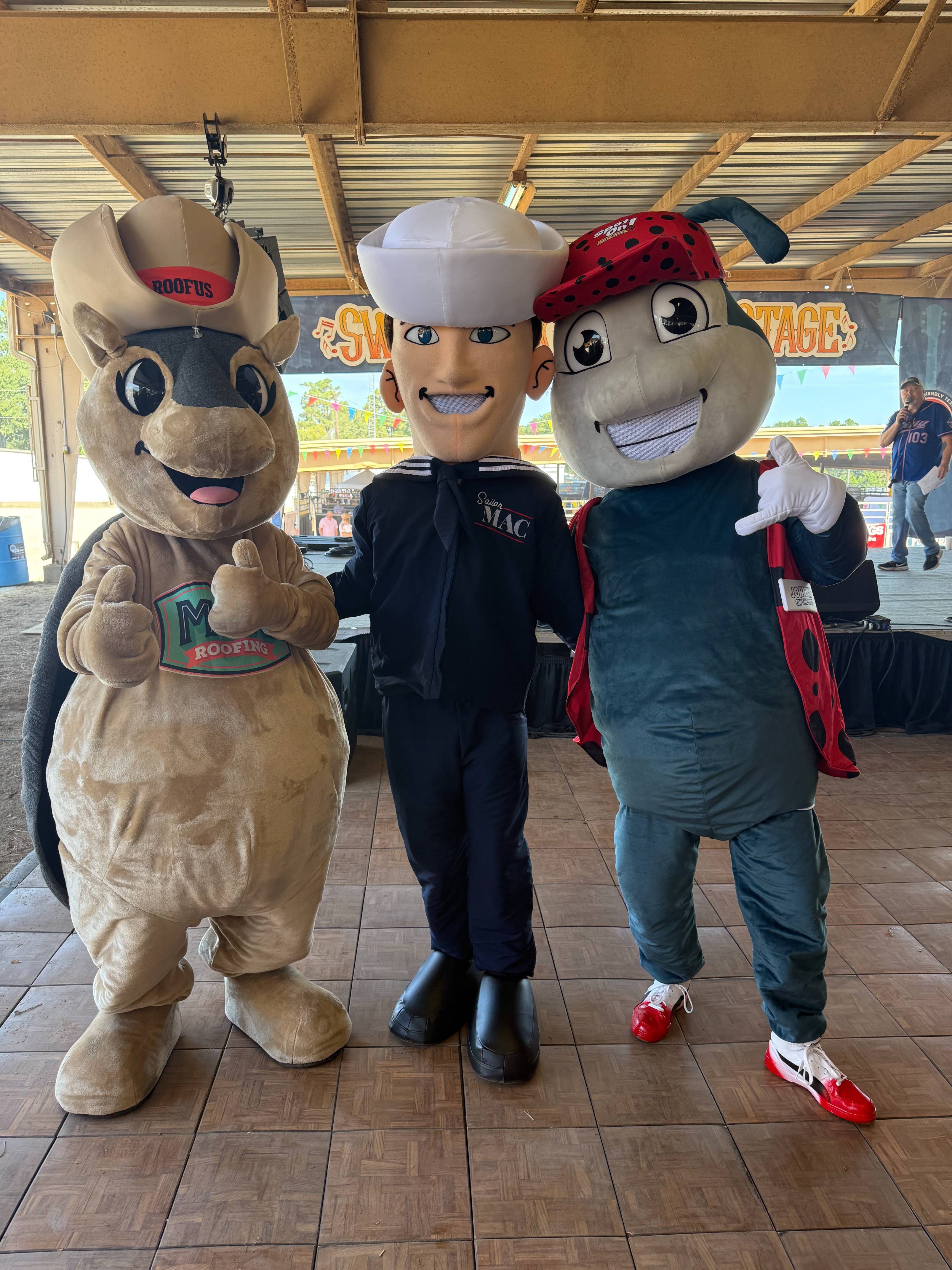 Three mascots posing on a stage.