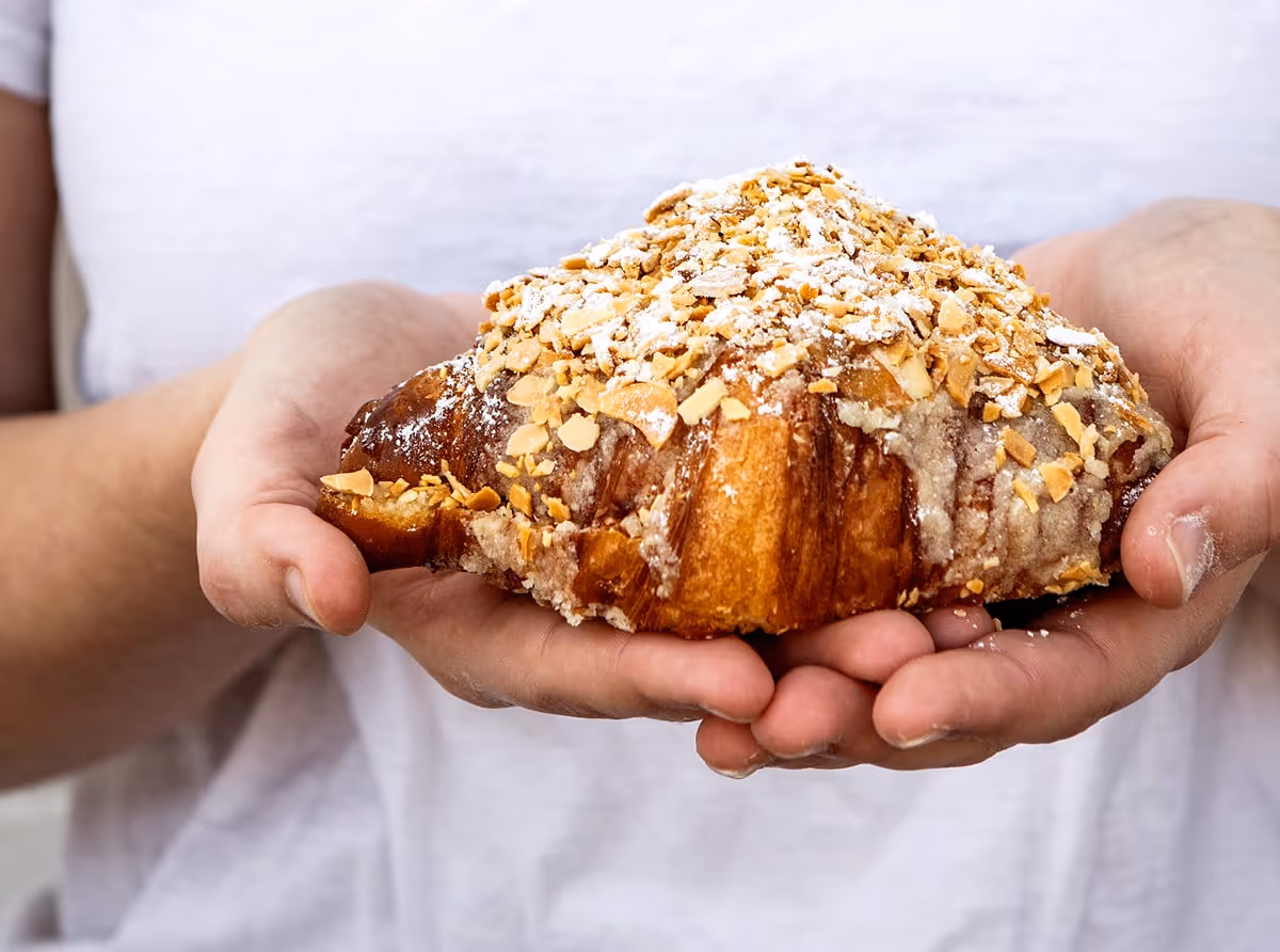 Hands holding an almond croissant