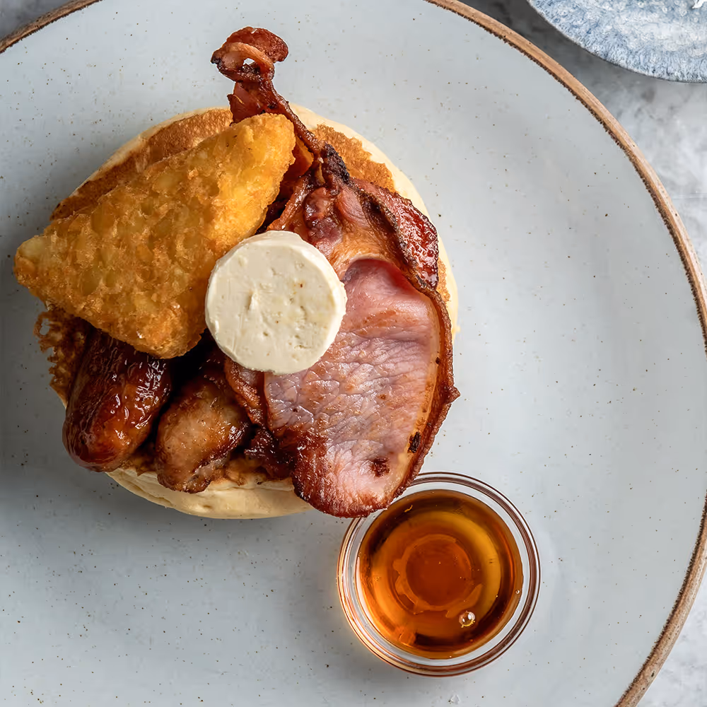 Fego Cafe Savoury Stack Pancakes with 3 buttermilk pancakes, grilled Cumberland sausage, bacon, hash brown, maple butter & maple syrup