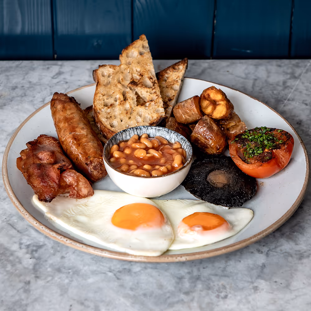 Fego Cafe Full English breakfast with grilled bacon, Cumberland sausage, 2 eggs your way, smashed potatoes, tomato, mushroom, baked beans & toasted sourdough