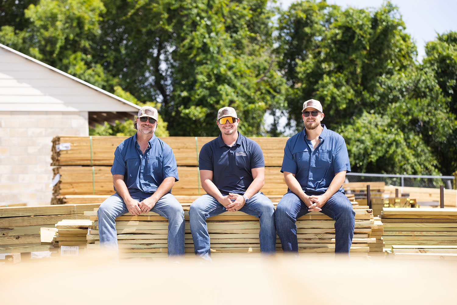 Elle Gray Construction team sitting on stacked lumber – licensed Florida contractors specializing in new home construction, remodels, and renovations in Pasco, Hernando, and Hillsborough counties.
