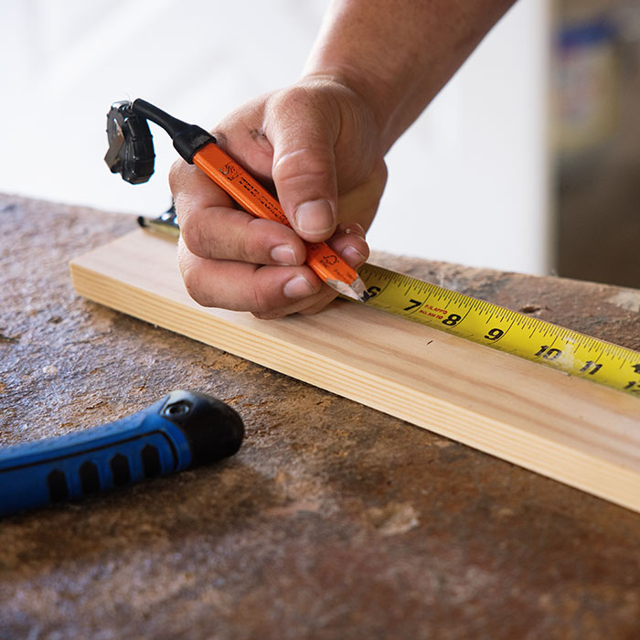Close-up of Elle Gray Construction measuring and marking lumber for a custom home project in Florida.