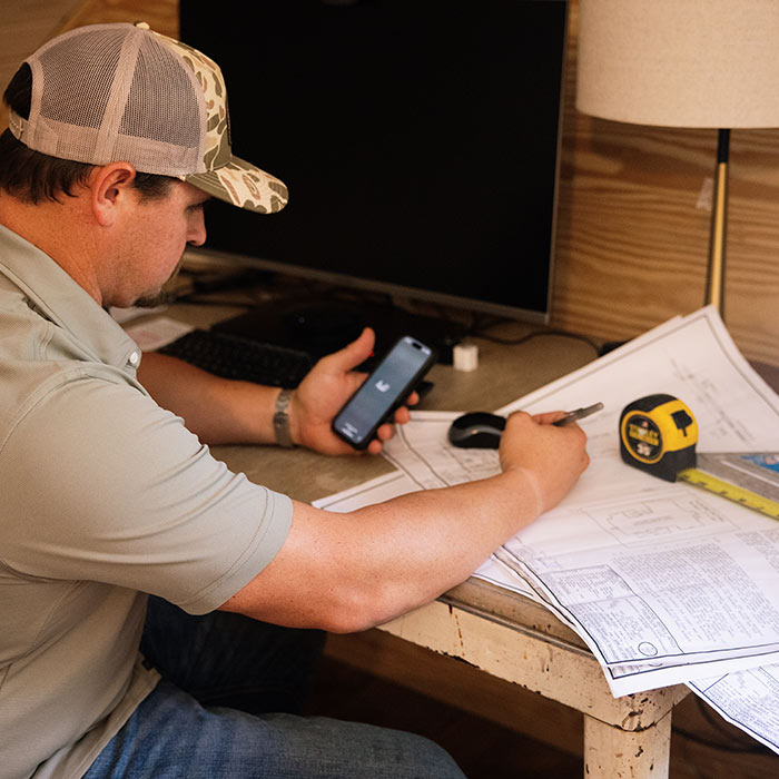 Elle Gray Construction owner reviewing blueprints and making client calls for a home renovation in Florida.