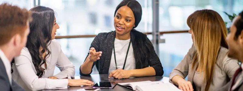 Young professionals around a table discussing how to keep C-suite Engagement for Customer Advocacy Success.