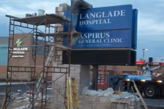 Sign repairmen on a ladderusing scaffolding to fix a sign