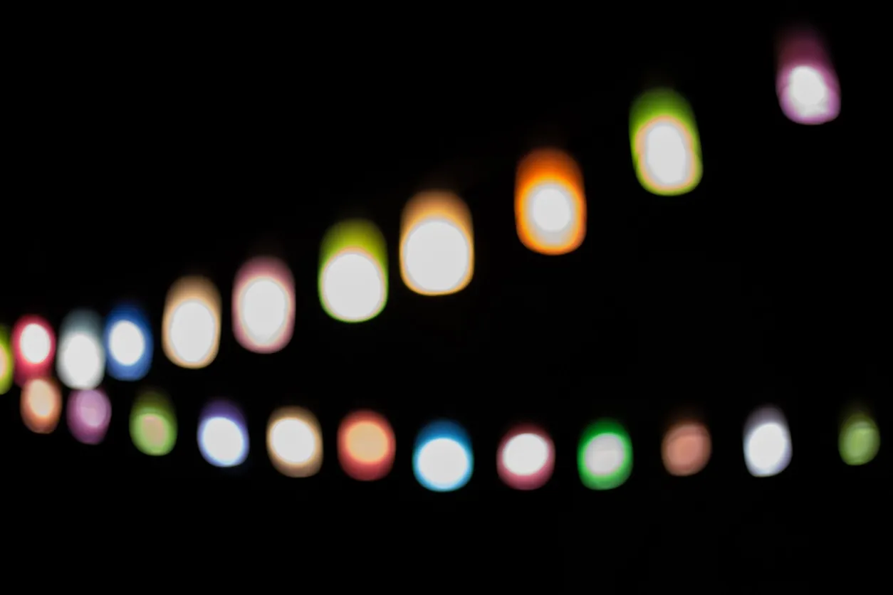 A close-up, dark and blurry photo of colorful, half-moon-shaped lights in shades of blue, green, and orange