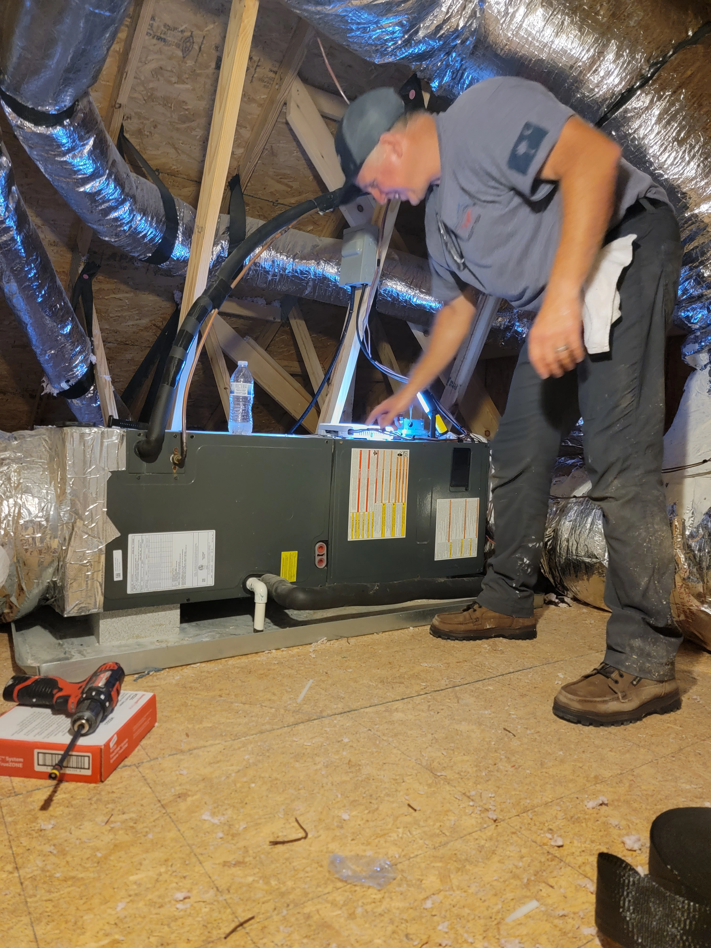 A man wearing a blue shirt is engaged in maintenance work on a furnace.