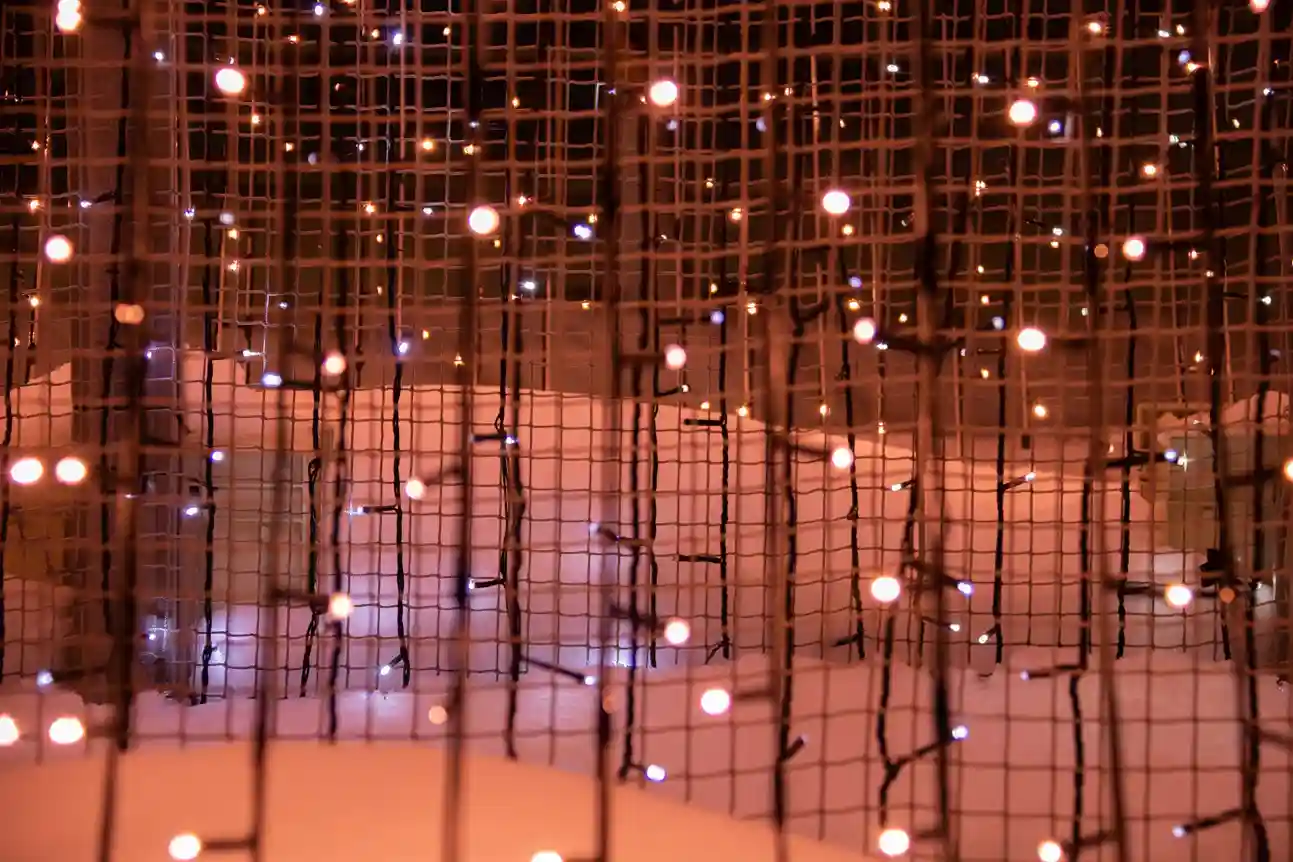 A close-up, out-of-focus shot of a decorative light installation made of a grid of small, glowing orange and white lights.