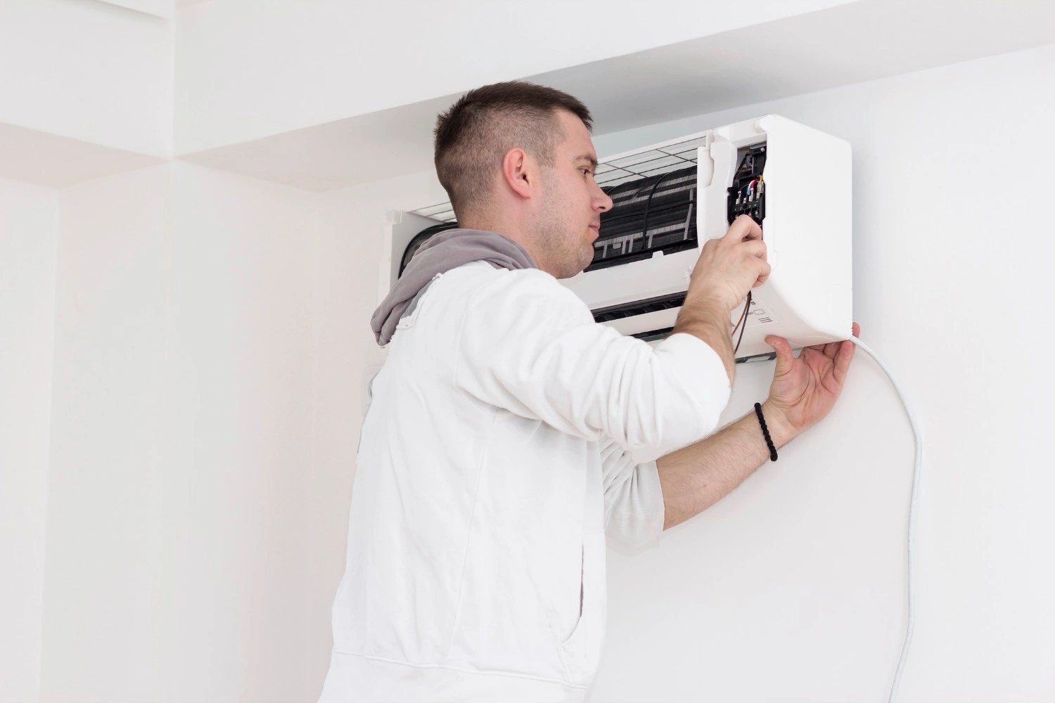 Man repairing a wall-mounted indoor AC unit.