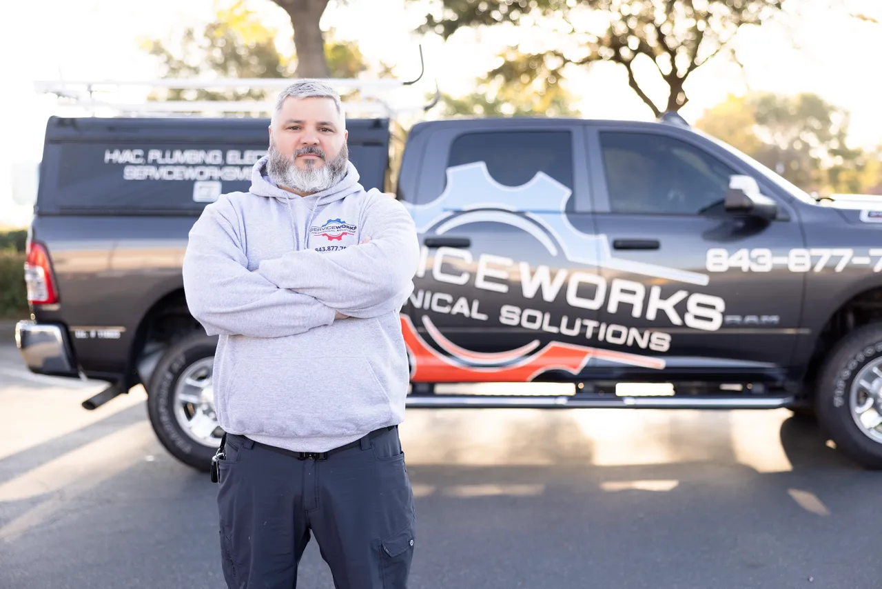 A ServiceWorks technician is standing in front of a company truck.