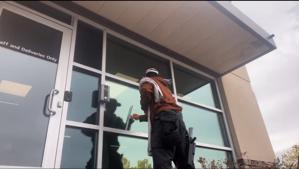 Residential window cleaning technician squeegeeing a two-story home
