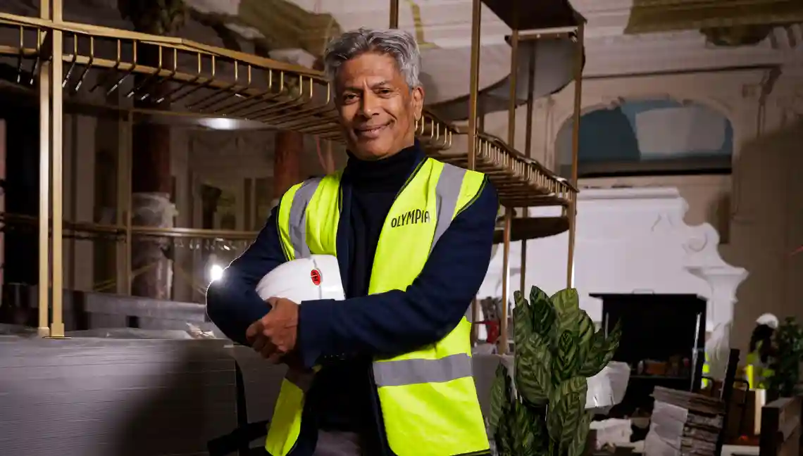 Des Gunewardena smiles at the camera wearing hi-vis PPE ileaving on an under-construction bar