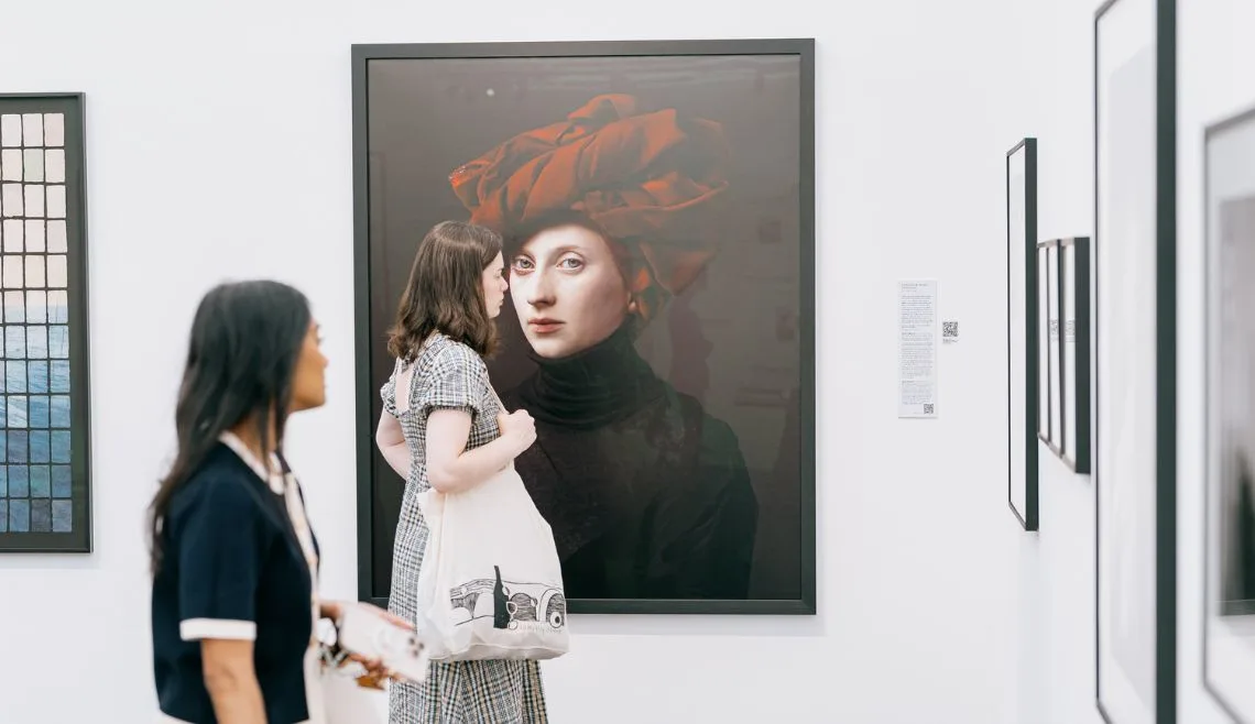 Two women looking at photography exhibited at Photo London fair.