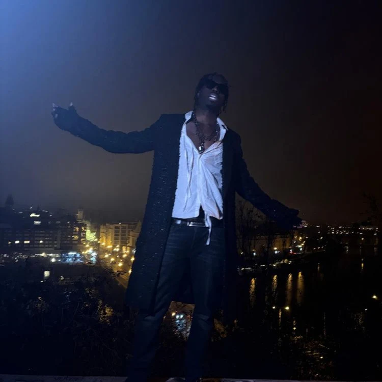 Fimiguerrero standing on rooftop with arms open.