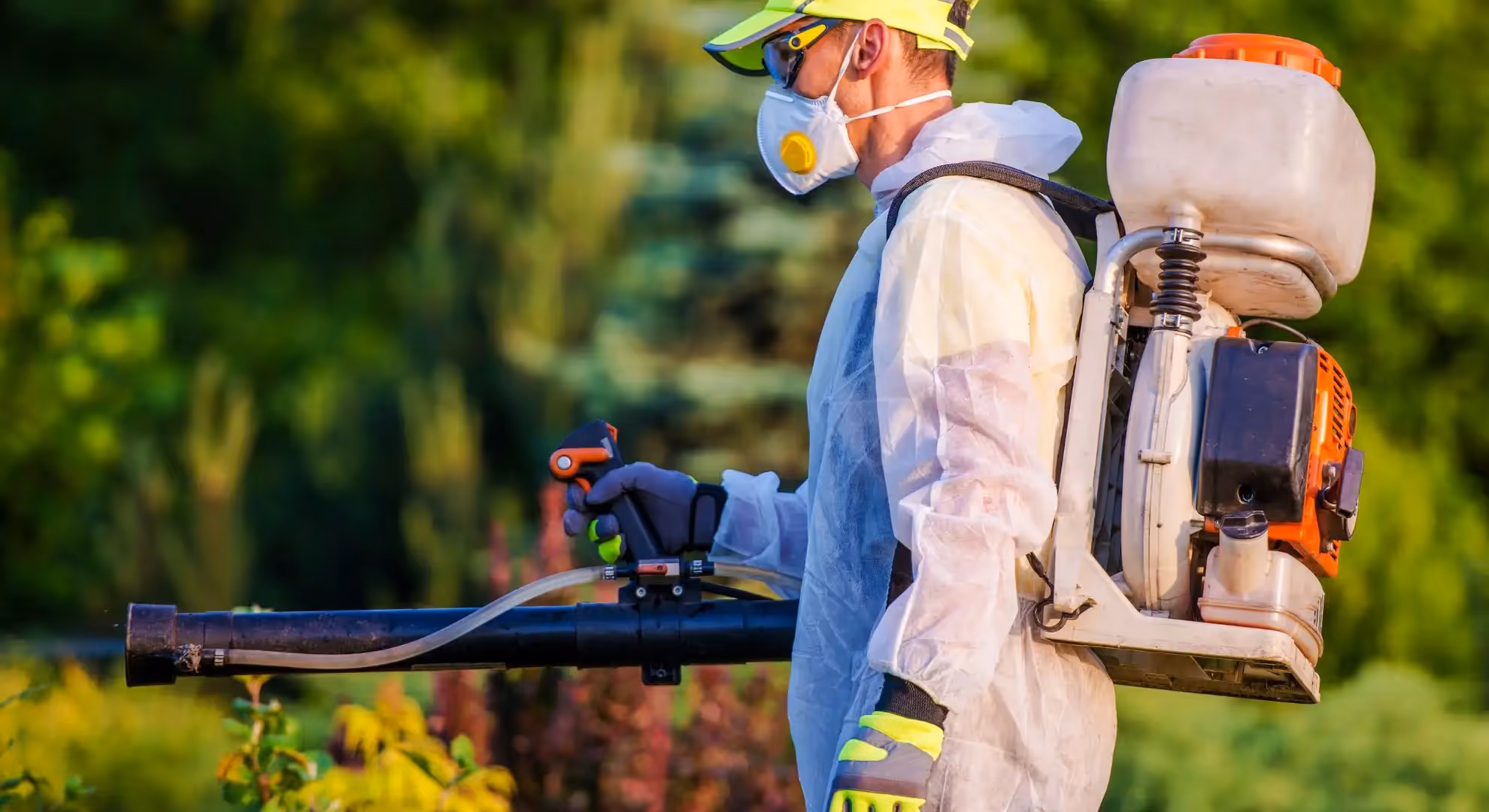 A person spraying for pests outdoors.