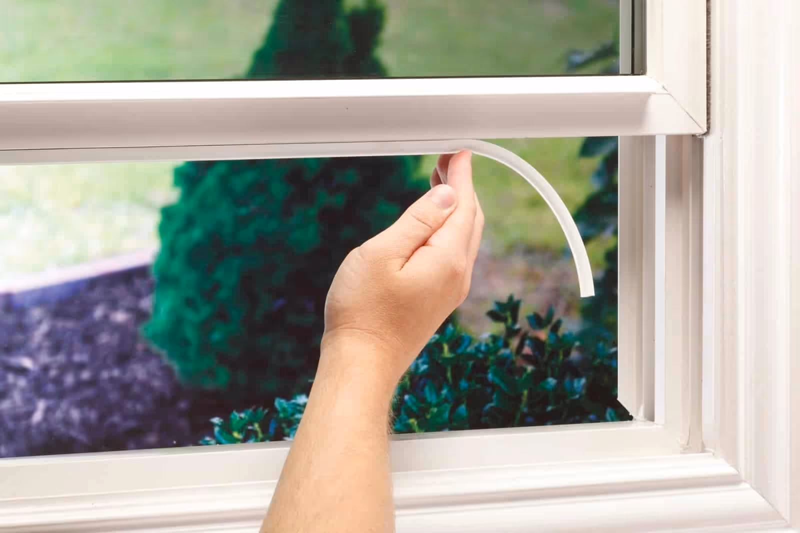 A person installing weatherstripping on a window.