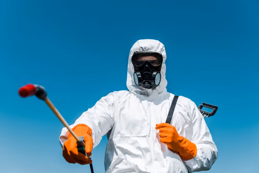A professional in a hazmat suit holding a sprayer.