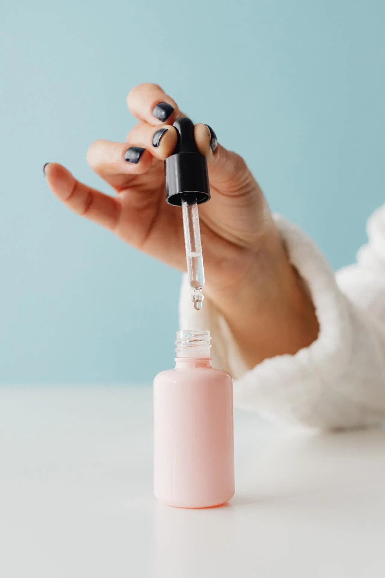A close-up of a hand preparing a dropper of aromatic oil to be used in a therapeutic foot treatment.